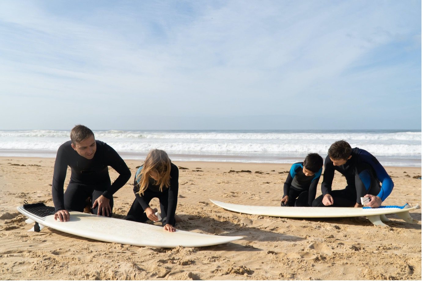 surfers waxing their surfboards