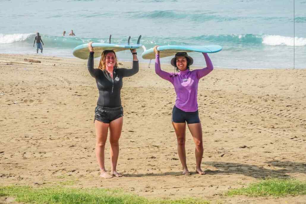two guest at the beach carrying surfboards