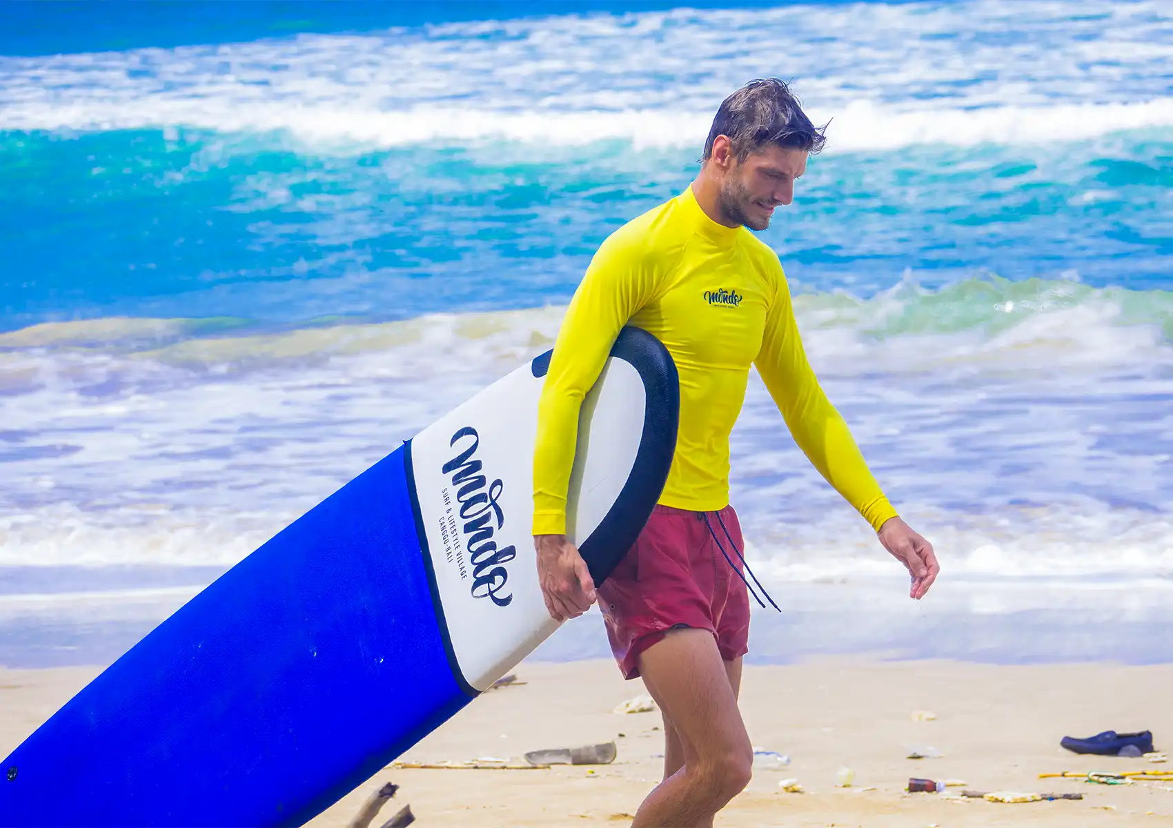ntermediate surfer carrying a funboard after a surf session at a surf camp Bali.