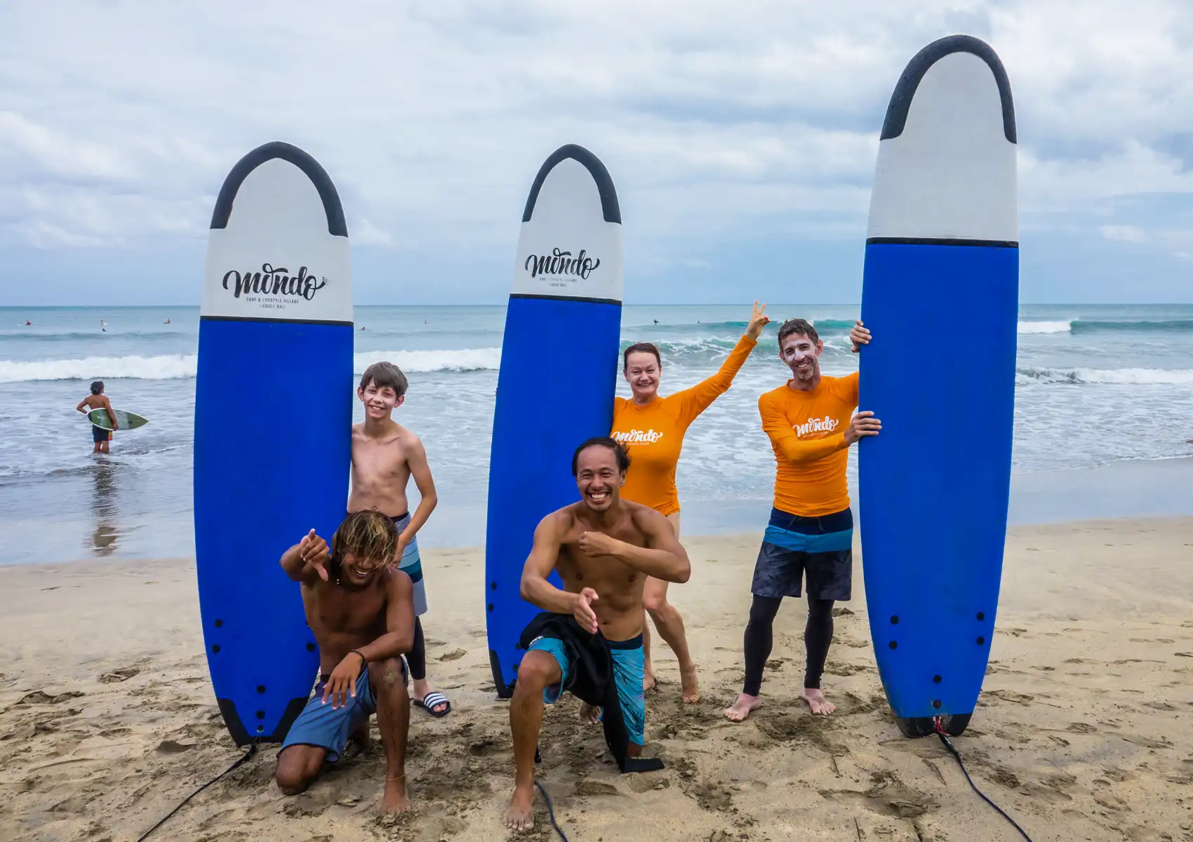 Group of surfers posing with surfboards after a surf camp Bali session on the beach.