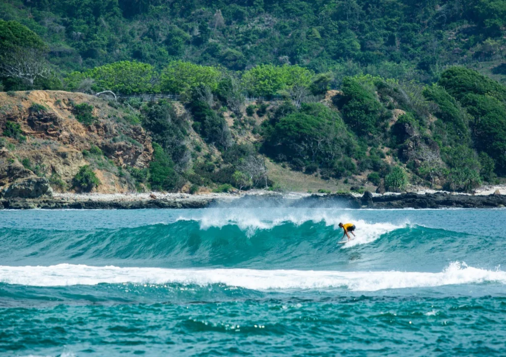 Surfer riding Bali reef break waves during the dry season at a surf camp in Bali.