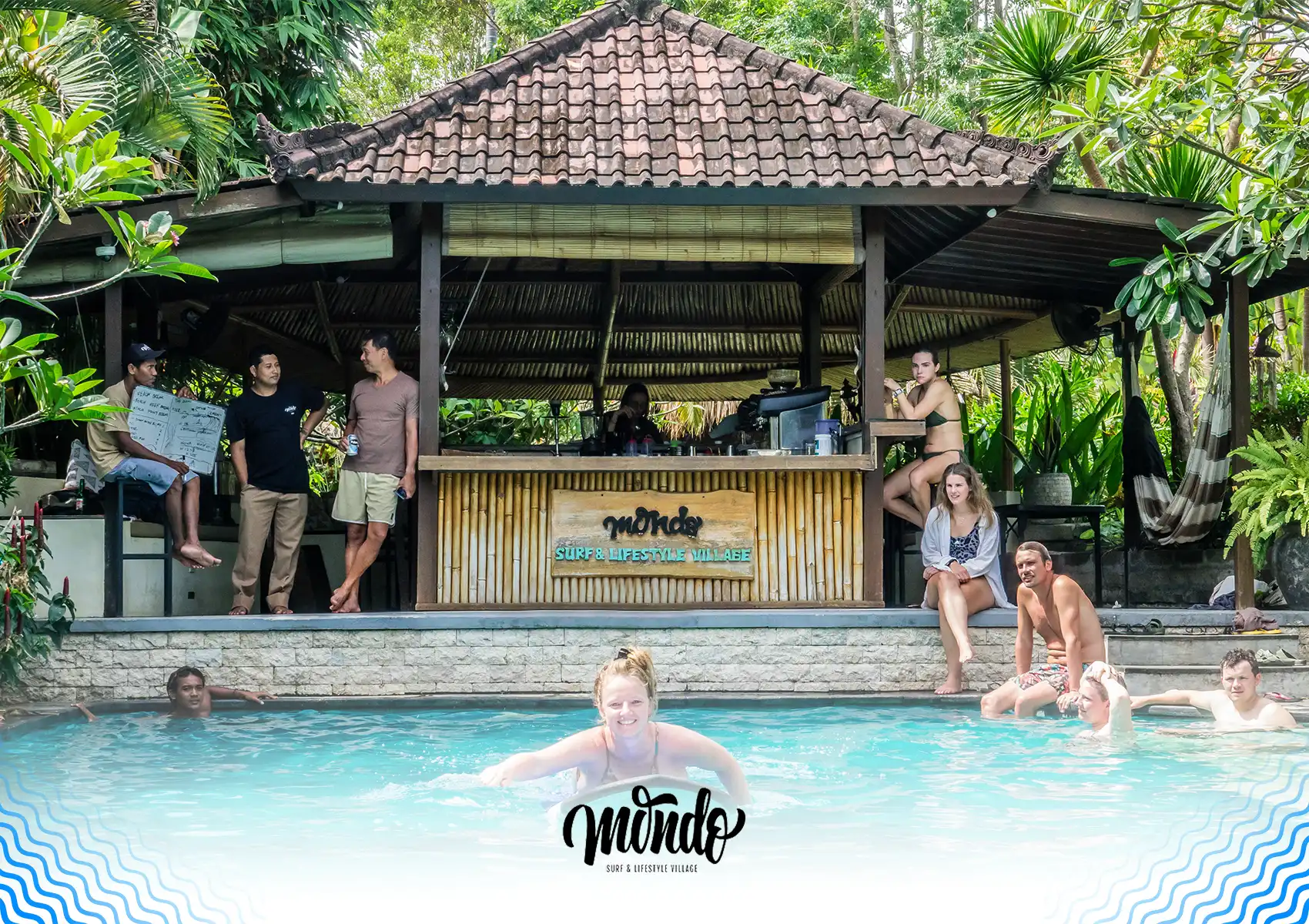 Guests relaxing by the swimming pool and traditional bamboo bar area at Mondo Surf & Lifestyle Village, a popular surf camp Bali.