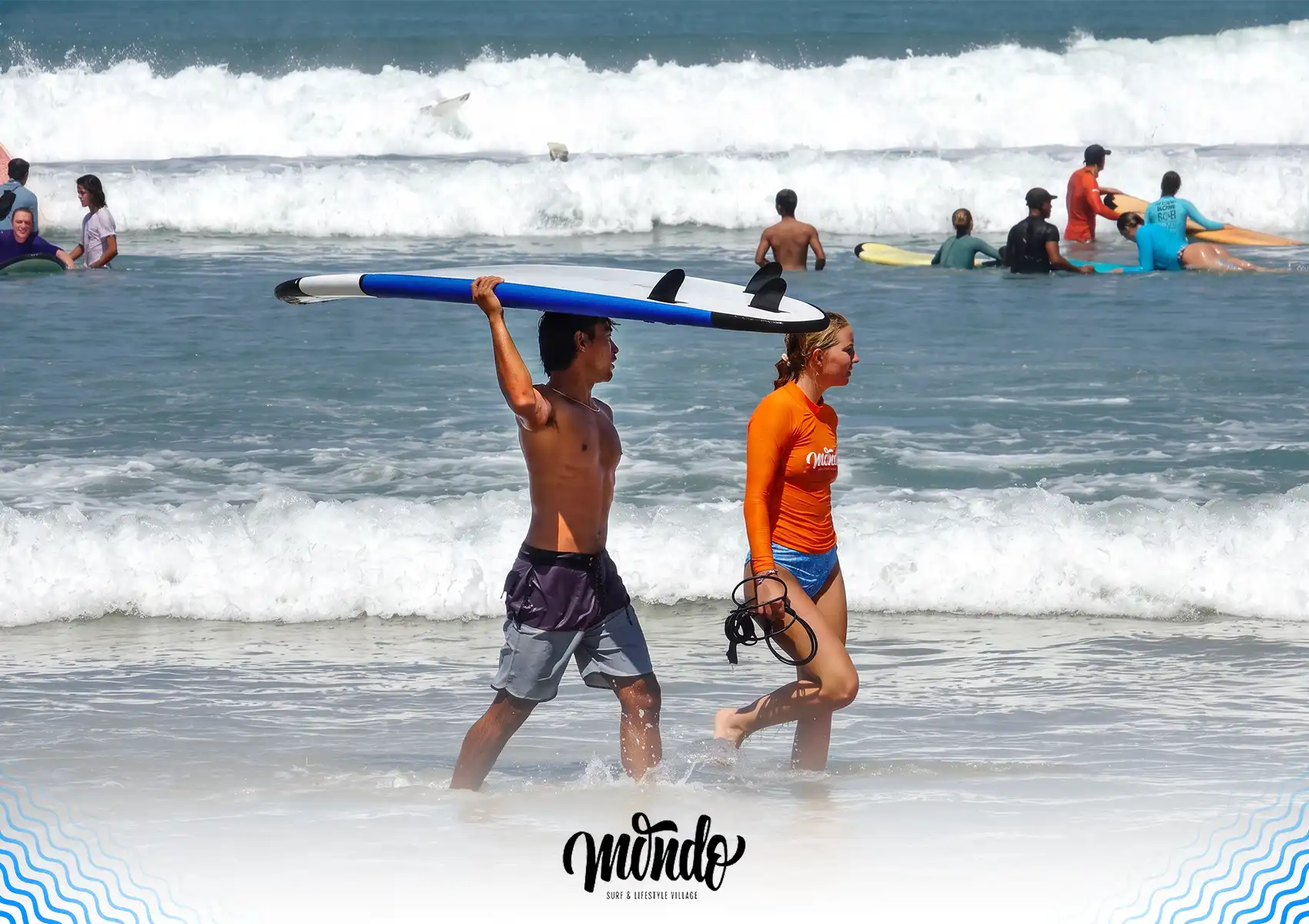 An instructor carrying a blue surfboard on his head while walking out of the shallow ocean water with a student after a lesson at a surf camp bali.