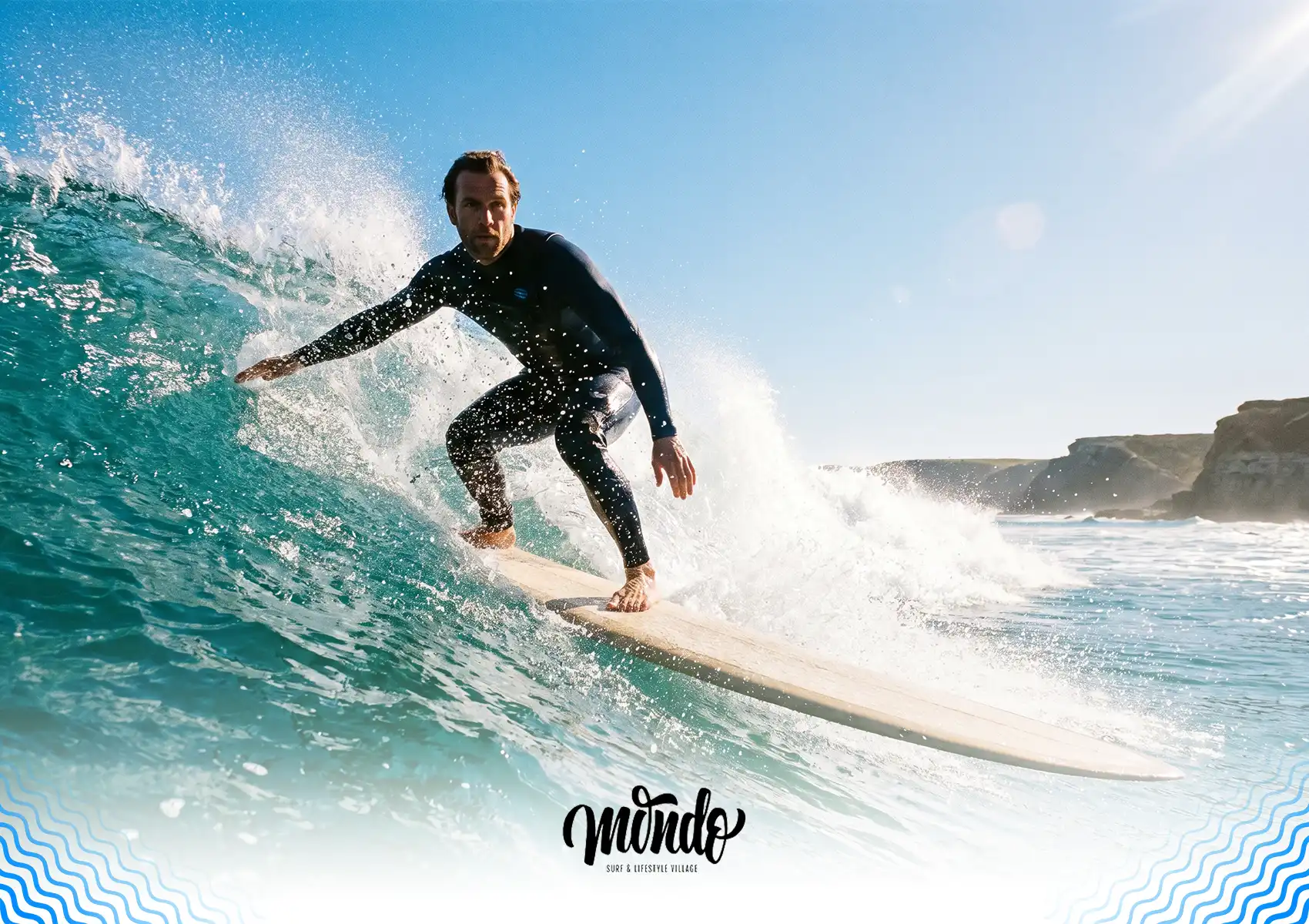 A male surfer in a black wetsuit balancing on a longboard while riding a clear blue wave under bright sunlight during high tide at a surf camp bali.