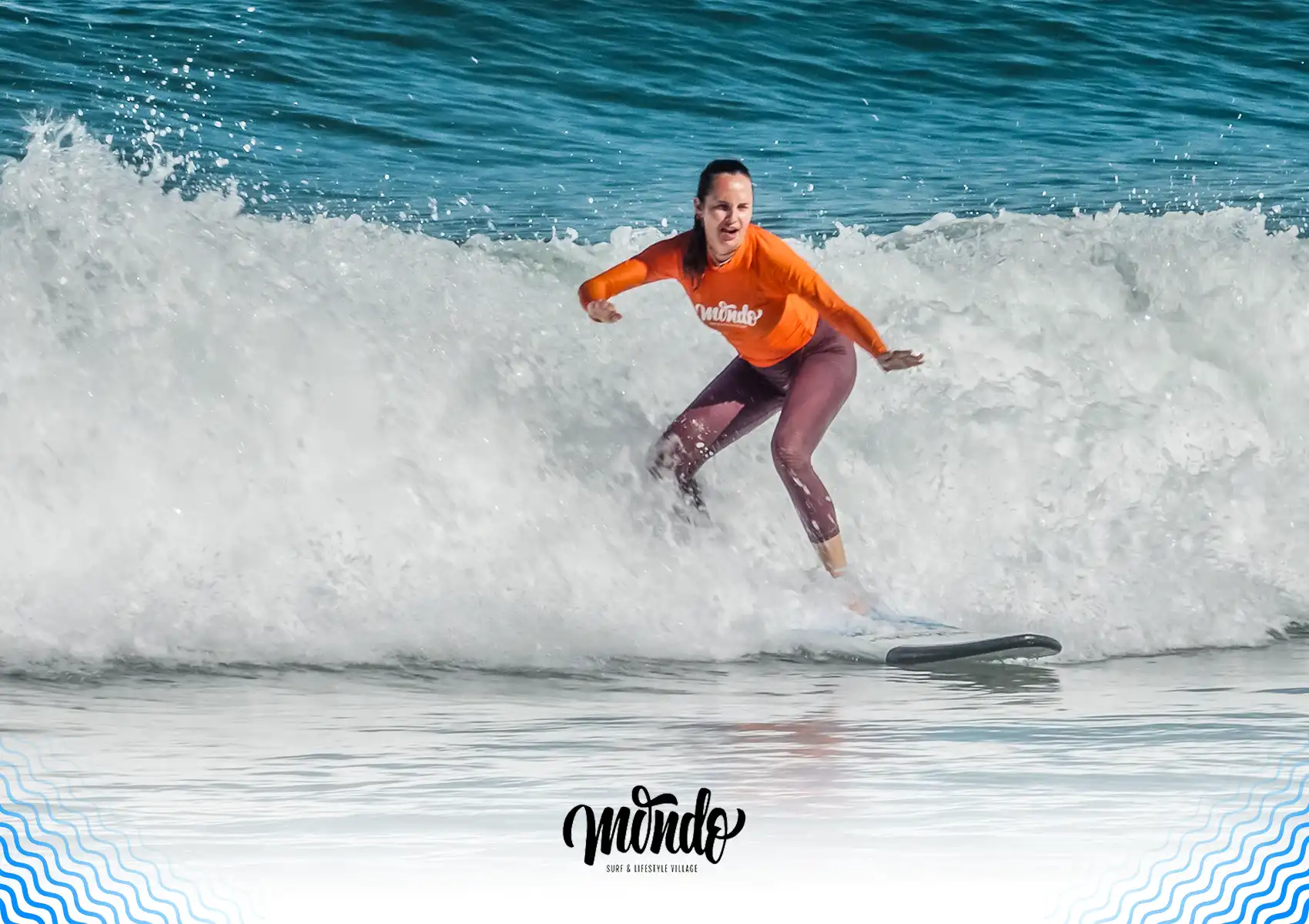 A female surfer wearing an orange rash guard riding a wave on a surfboard during a session at a surf camp Bali.