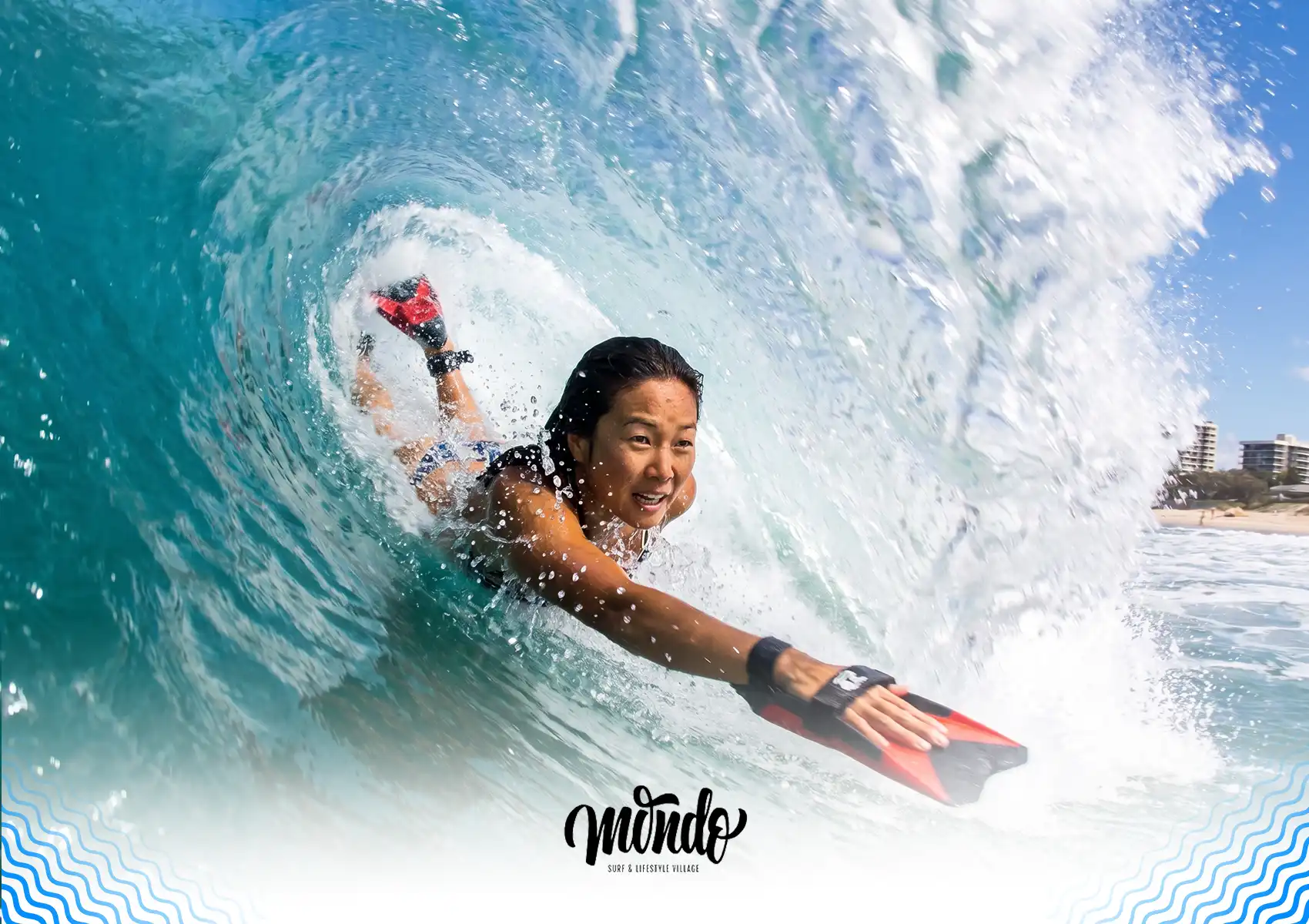 A woman bodysurfing inside the barrel of a clear blue wave using a red handplane at a surf camp Bali.